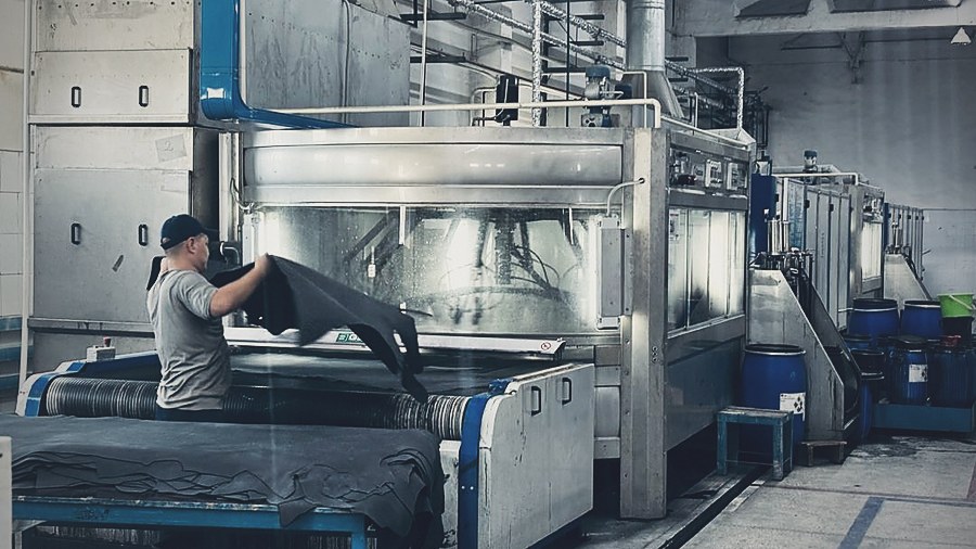 An operator handling finished black leather at the finishing line